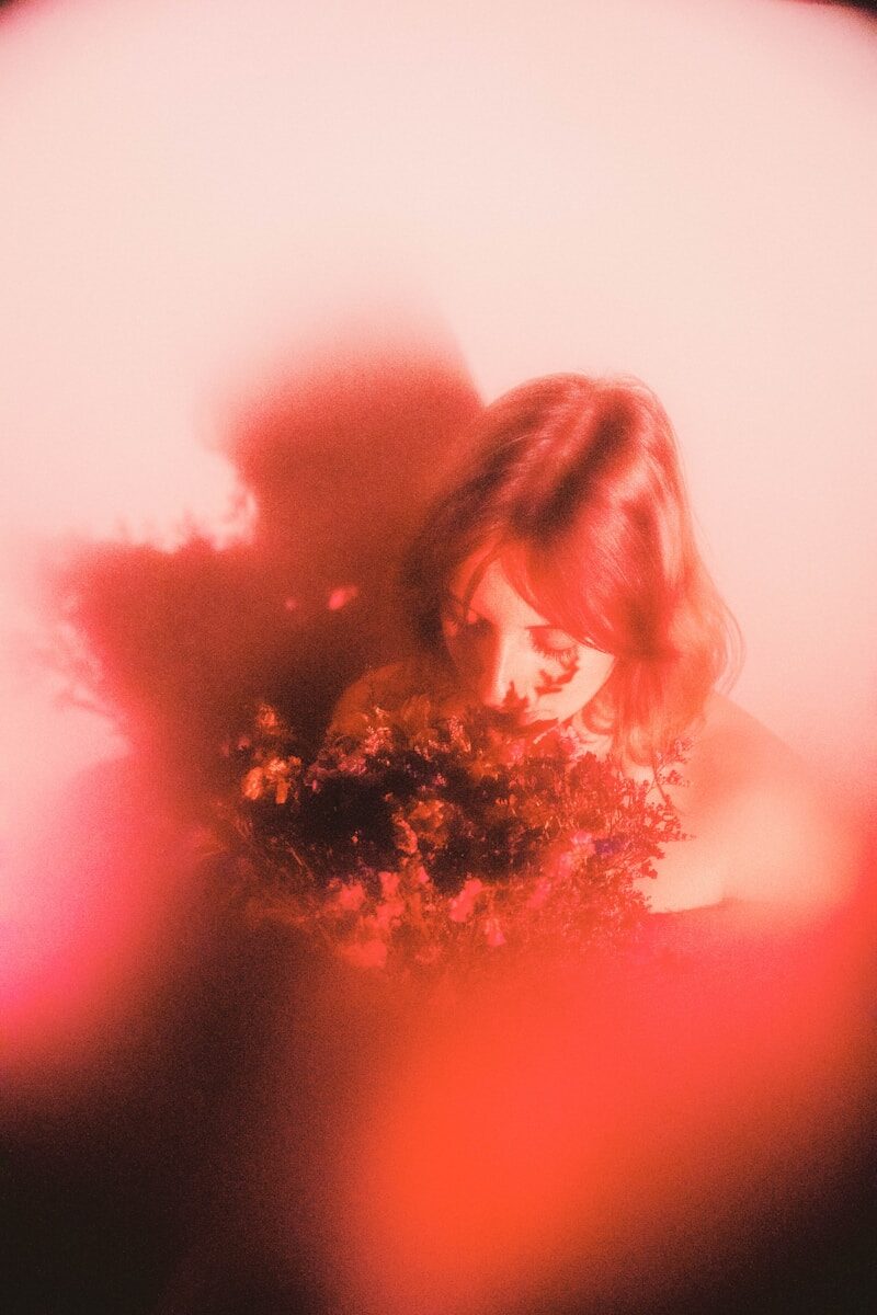 Woman with flowers amidst red hues.